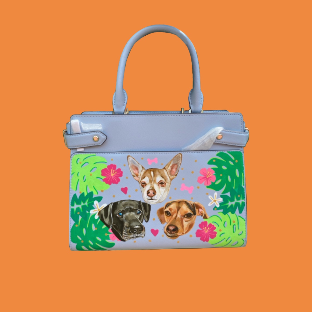 Custom painted blue handbag with three dog portraits, tropical leaves and pink flowers.